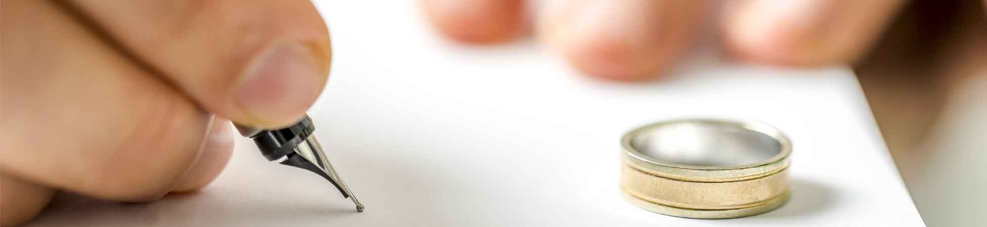Pen signing legal documents with a wedding ring nearby